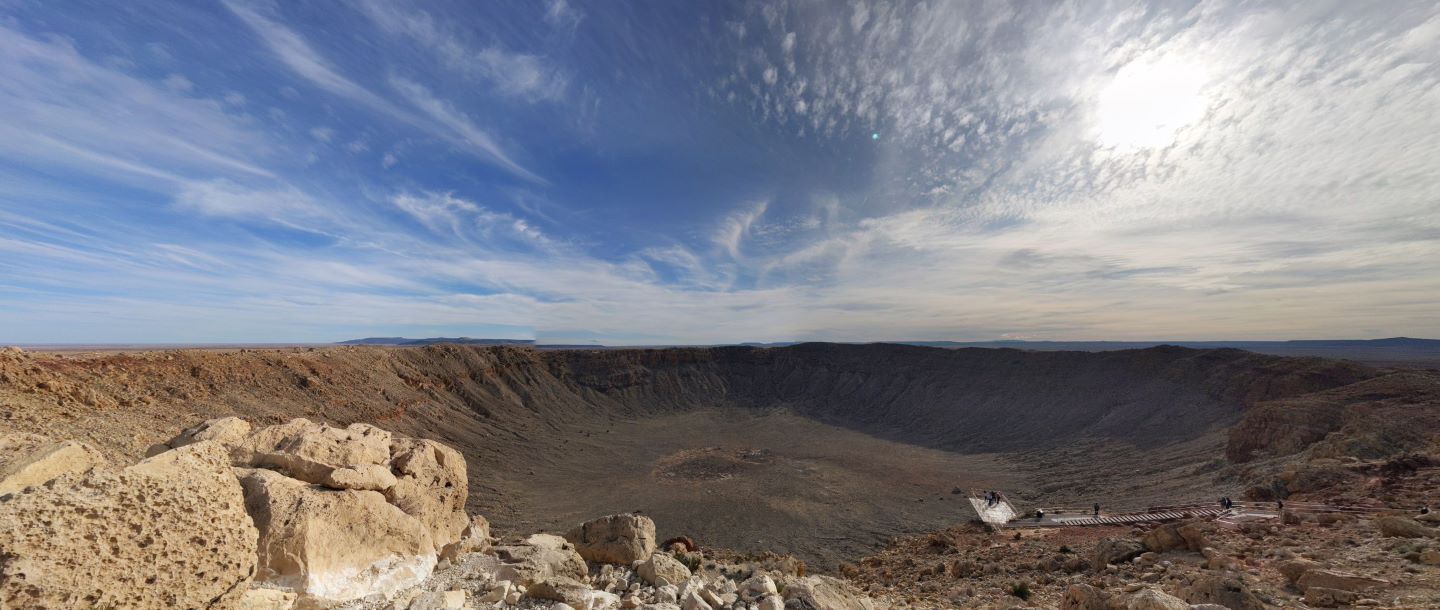View of a meteor crater with people looking at the large area in the background