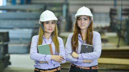 women in hardhats holding books and a tablet