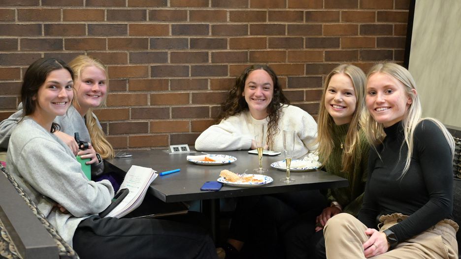 Five students at a table smiling and posing at the 2022 Undergraduate Research Symposium reception