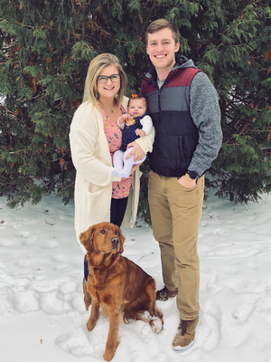a person and person holding a baby and a dog in the snow