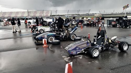 Formula SAE race cars and crew at the 2016 Endurance competition on a cloudy and rainy day