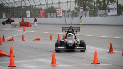 Formula SAE driver in open wheel race car on the side of the race track
