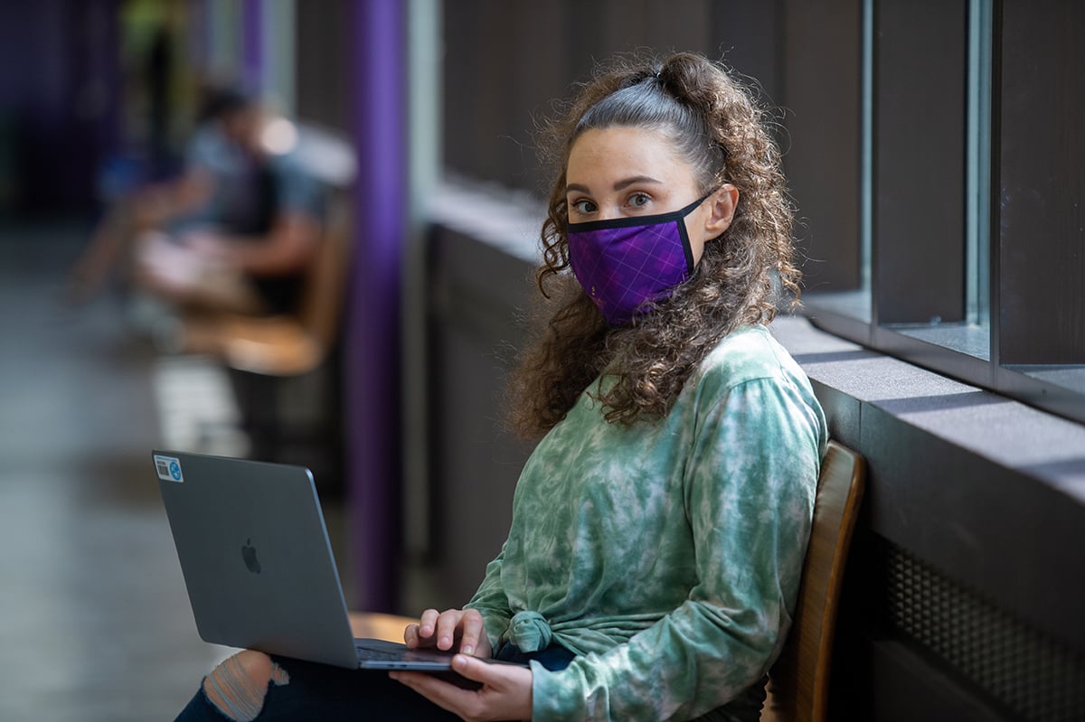 a person wearing a face mask and using a laptop