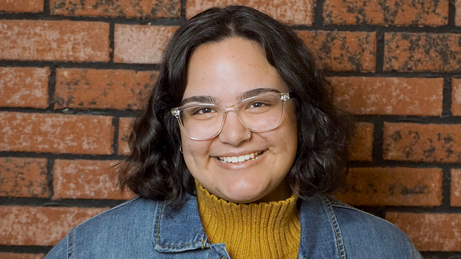 a person smiling in front of a brick wall