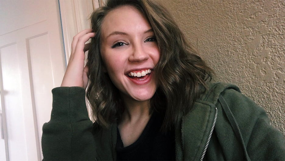 a person smiling with her hand on her head