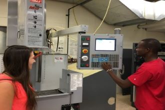 Two students working on the computer numerical control machine in the manufacturing automation laboratory