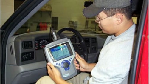 A student doing a diagnostic check on a vehicle in the automotive lab