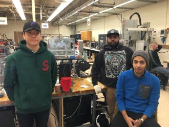 Manufacturing engineering students posing for a group photo at their work station in the manufacturing automation laboratory