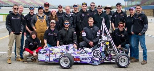 The Minnesota State University Mankato formula SAE team posing with their race car on the race track