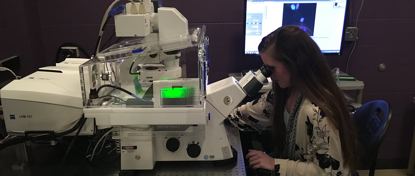 Student looking through a Confocal microscope in the biology lab