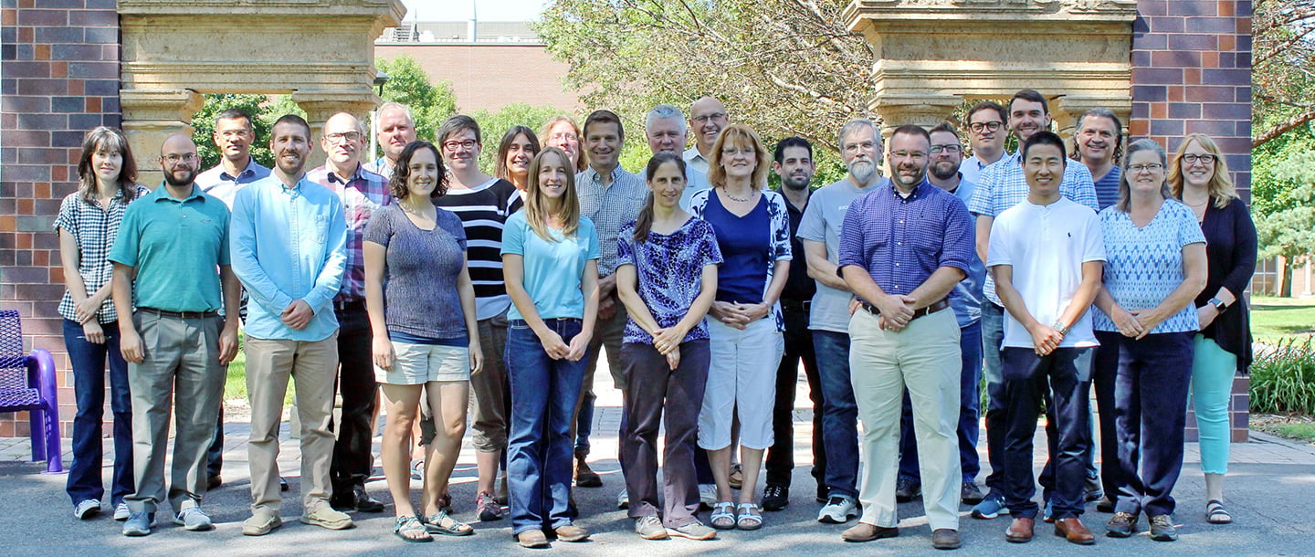 the faculty and staff of the Biological Sciences department posing outside on campus by the Alumni Arch