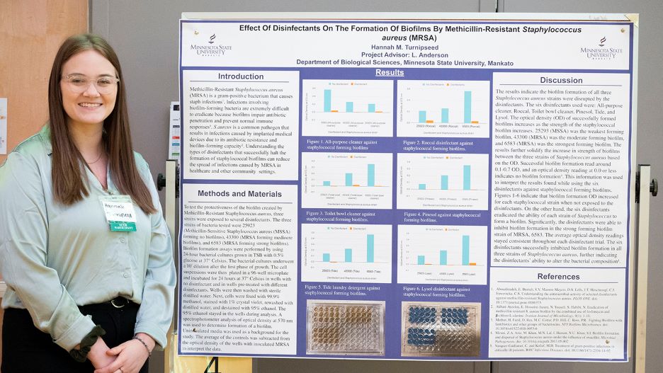 Hannah posing next to her presentation board at the 2022 Undergraduate Research Symposium