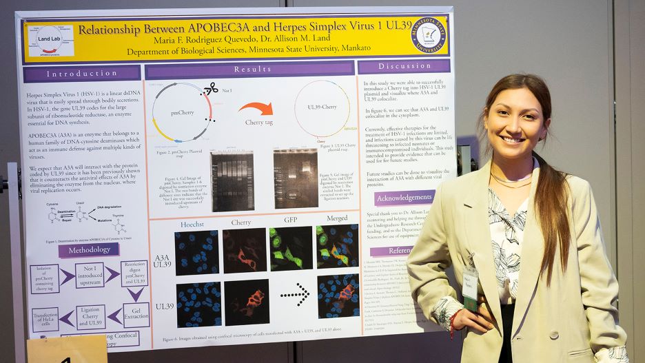 Maria posing next to her presentation board at the 2022 Undergraduate Research Symposium