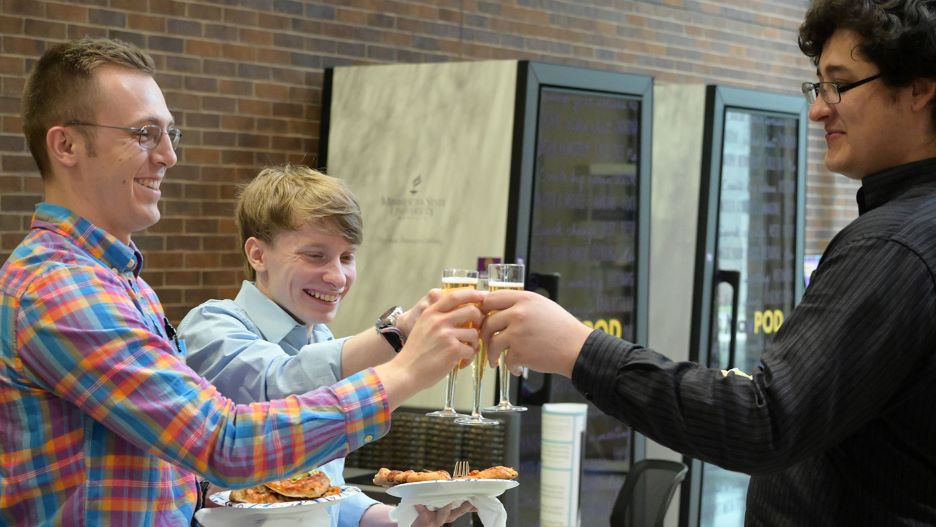 students making a toast with their glasses in the food line at the reception