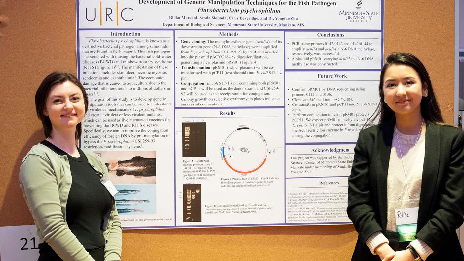Ritika and Carly posing next to their presentation board at the 2022 Undergraduate Research Symposium