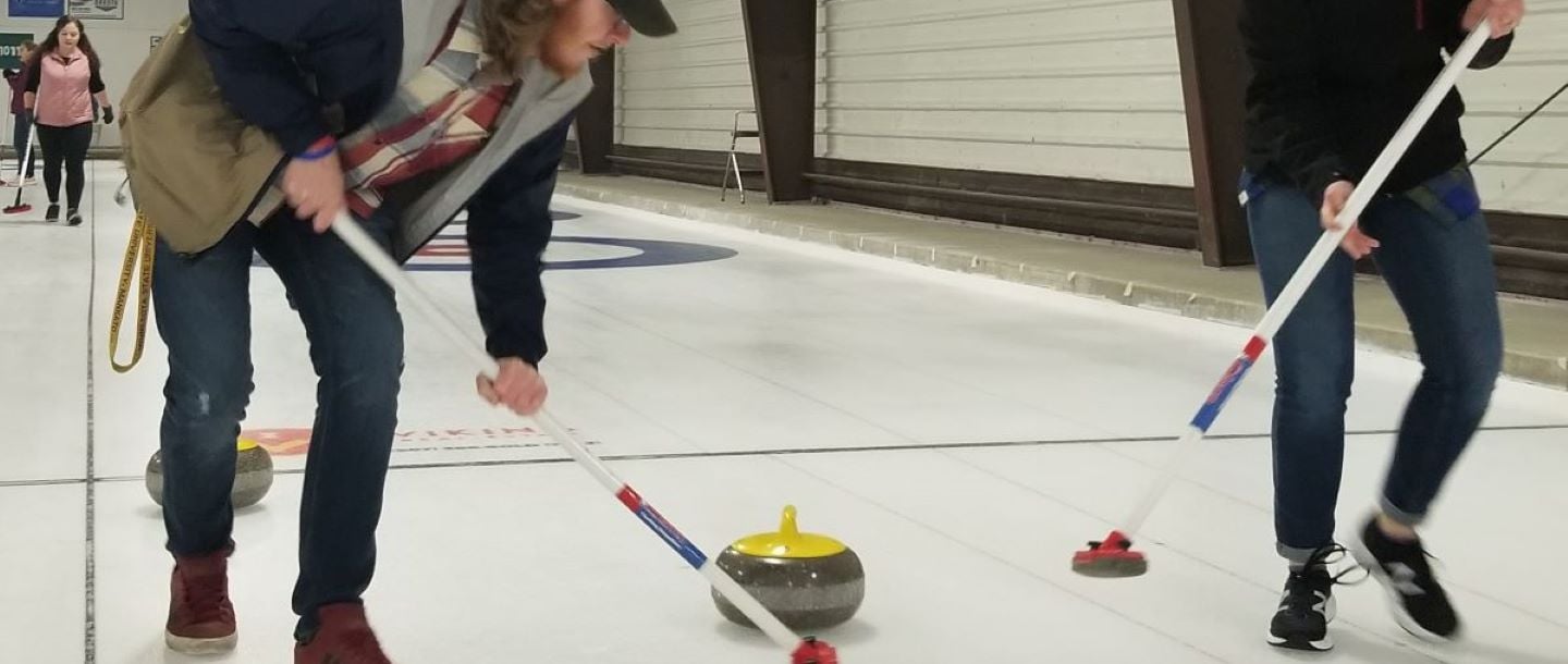 ACS curling students trying to make the path smooth for the stone with their curling broom