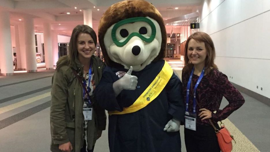 Two students posing with the chemistry ambassador mascot
