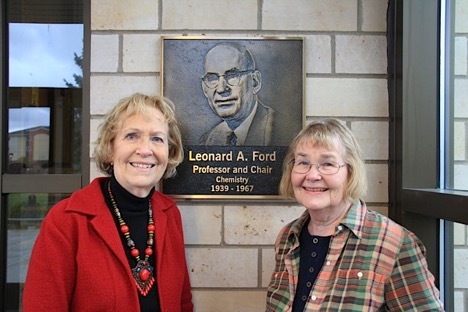 women standing in front of a plaque