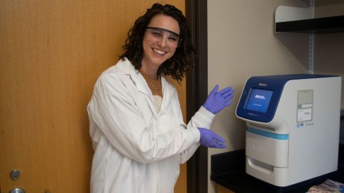 student posing and smiling in the lab while carrying out a PCR test