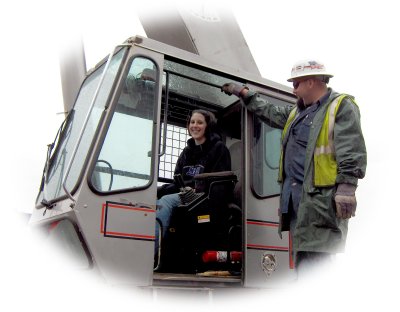 A construction worker mentoring a student on operating heavy machinery on the job