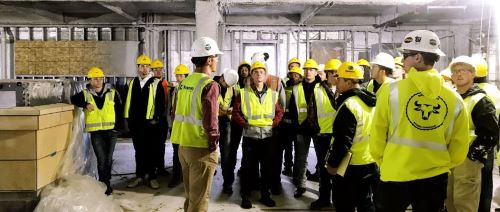 Students on a tour at the Eide Bailly construction site wearing construction helmets and vests