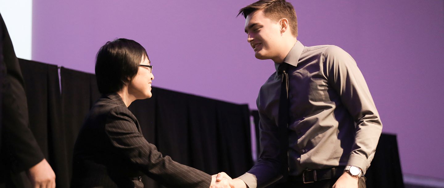 Student shaking hands with faculty at the Scholarships award ceremony