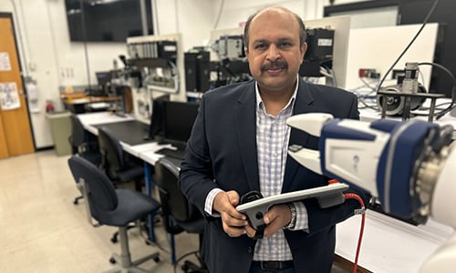 Professor Bhushan Dharmadhikari posing in the robotics lab at Minnesota State University, Mankato
