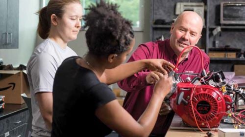 Ron Ulseth, Director of Academics and Research, Iron Range Engineering, working with two students on repairing a small engine in the shop