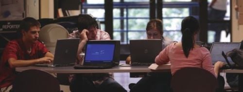 Students working together at a table with laptops