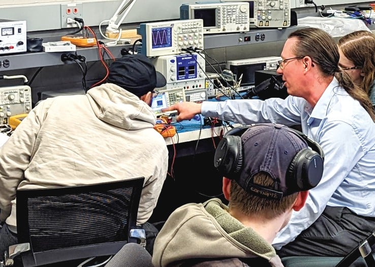 a group of people in a room with electronic equipment