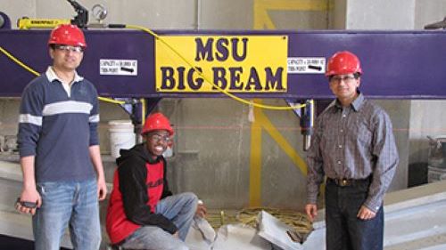 Students and professor posing by their big beam during the PCI big beam competition