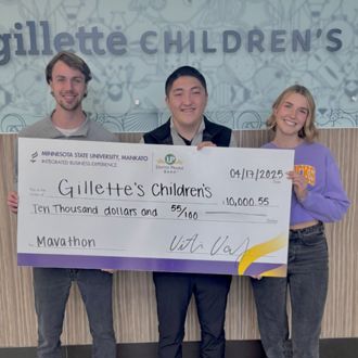 Three Mavathon student leaders posing for a photo holding a big check from Gillette Children's for $10,000