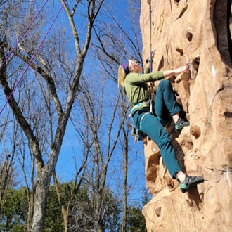 Riley Jones rock climbing outside on a sunny day